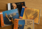 Quatre CD japonais authentiques avec OBI strips posés sur une table en bois, illustrant des éditions audiophiles.