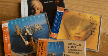 Quatre CD japonais authentiques avec OBI strips posés sur une table en bois, illustrant des éditions audiophiles.