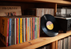 Collection de CD japonais Mini LP avec OBI à côté de vinyles sur une étagère en bois.