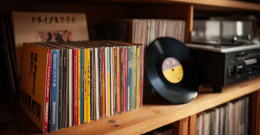 Collection de CD japonais Mini LP avec OBI à côté de vinyles sur une étagère en bois.