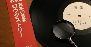 Vinyle japonais avec OBI rouge et matrice observée à la loupe sur une table en bois.