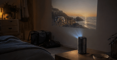 Nebula Capsule 3 posée sur une table de chevet dans une pièce sombre avec une projection modérée sur un mur clair