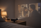 Philips NeoPix 160 Smart posé sur une table de nuit et projetant une série sur le mur d’une chambre sombre