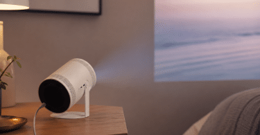 Samsung The Freestyle 2nd Gen posé sur un meuble et projetant une image sur un mur dans une pièce moderne