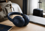 Casque JBL Tour One M3 posé sur une table avec ordinateur portable et accessoires de voyage