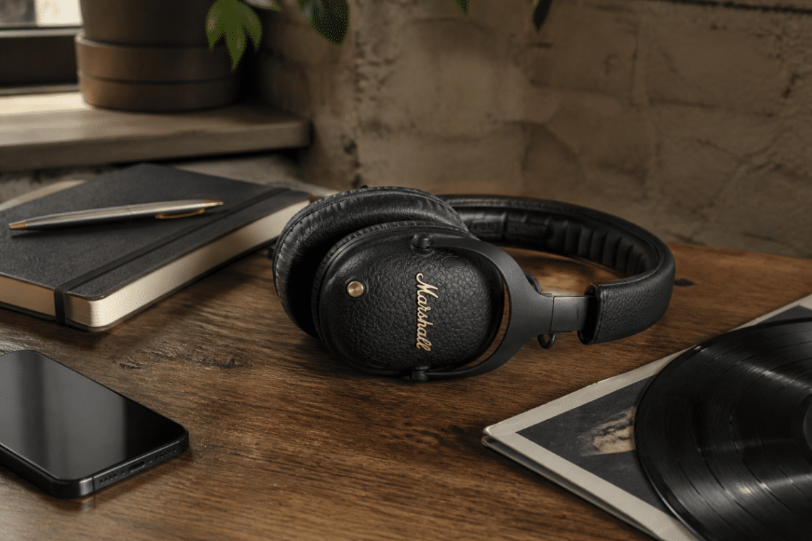 Casque Marshall Monitor III A.N.C. noir posé sur une table en bois avec un carnet, un smartphone et un disque vinyle
