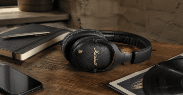 Casque Marshall Monitor III A.N.C. noir posé sur une table en bois avec un carnet, un smartphone et un disque vinyle